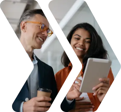 Two co-workers looking down at a tablet device and smiling